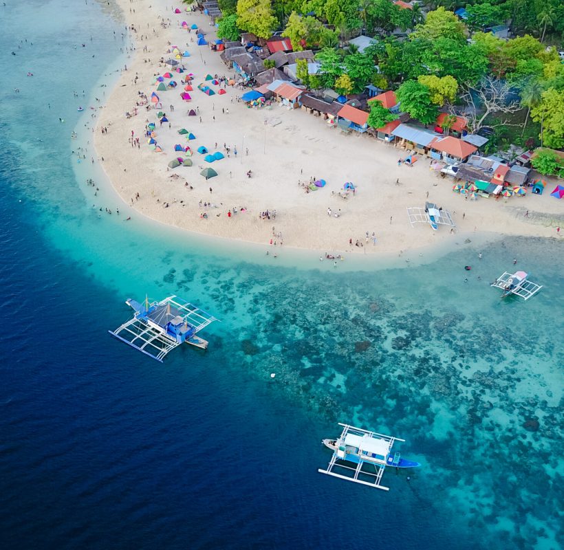 Aerial view of sandy beach with tourists swimming in beautiful clear sea water of the Sumilon island beach landing near Oslob, Cebu, Philippines. - Boost up color Processing.
